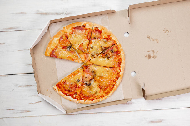 Pizza pieces in a cardboard box. white wood background. Food concept. View from above. - Foto, Bild