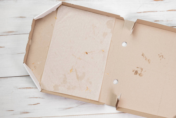 Empty open pizza box. White wooden background. Eaten pizza. Top view. - Photo, image