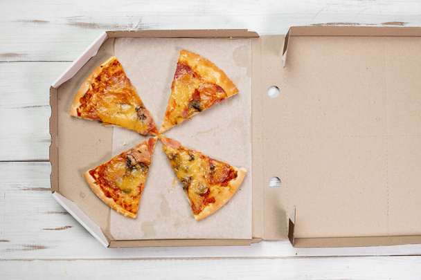 Pizza pieces in a cardboard box. white wood background. Food concept. View from above. - Φωτογραφία, εικόνα