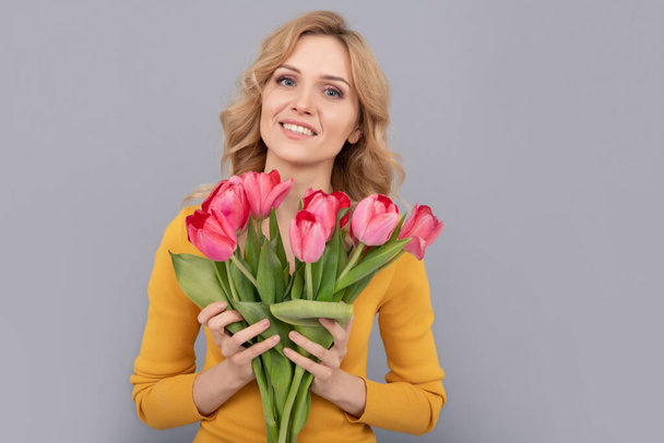 smiling girl hold flowers for spring holiday on grey background - Foto, Imagem