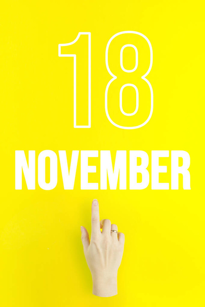 November 18th. Day 18 of month, Calendar date.Hand finger pointing at a calendar date on yellow background.Autumn month, day of the year concept - Zdjęcie, obraz