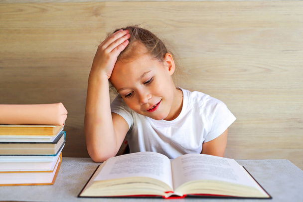 Schoolgirl girl reads books after school to know a lot - Fotó, kép