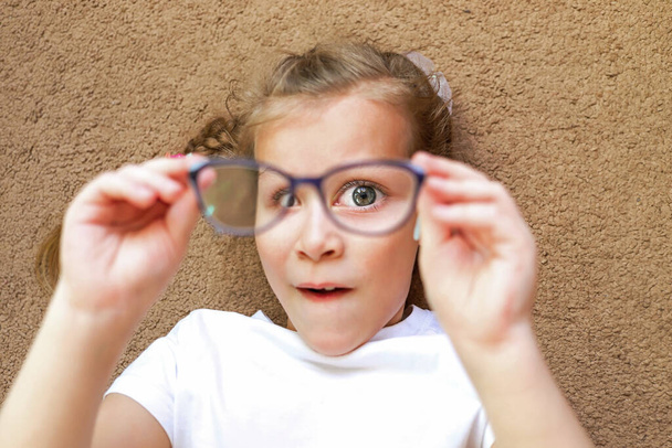 the girl looks through the optical lenses of the glasses sees big eyes - Foto, Imagem