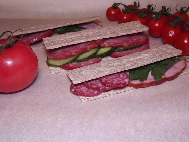 szendvics különféle típusú kolbászokkal és zöldségekkel, gyors snack - Fotó, kép