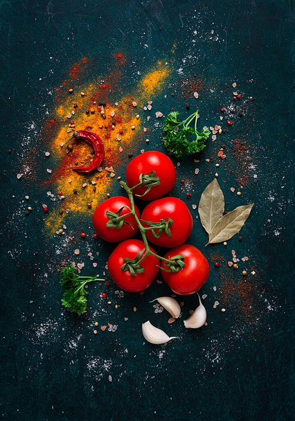 rama de tomate, sobre fondo verde oscuro, con especias, vista superior, fondo de alimentos, vertical, sin personas, - Foto, imagen