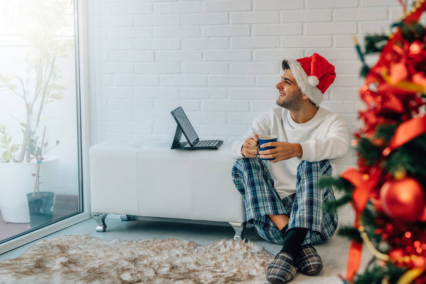 man in santa claus hat at home for christmas with laptop - Foto, Imagen