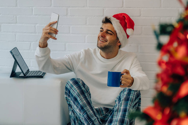 homem em casa com telefone celular fazendo videochamada no Natal - Foto, Imagem