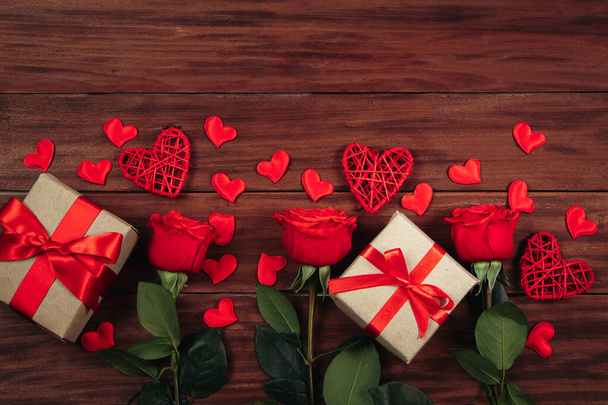 Rosas vermelhas e corações em fundo de madeira escura. Conceito de cartão postal do dia dos namorados. - Foto, Imagem
