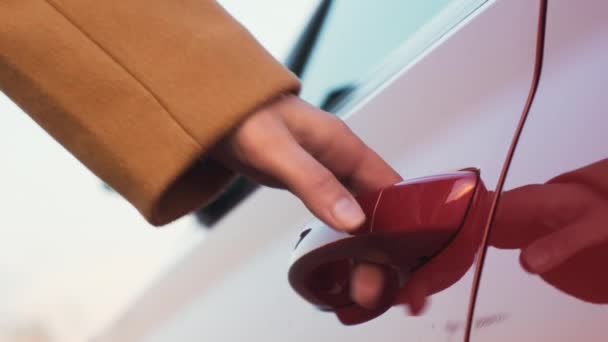 Μια γυναίκα φέρνει το χέρι της στο χερούλι της πόρτας του κόκκινου αυτοκινήτου και το ανοίγει, ξεδιπλώνοντας τον πλευρικό καθρέφτη. Ενοικίαση αυτοκινήτου έννοια  - Πλάνα, βίντεο