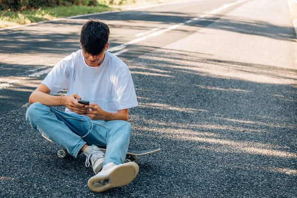 Junge mit Skateboard und Kopfhörer unterwegs - Foto, Bild