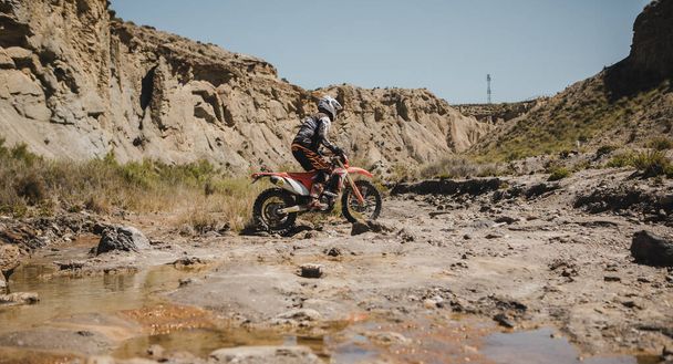 Almeria, Spain - May 5th 2021: Motocross rider crossing a river in Tabernas desert during Dunlop Xperience showroom and test in Almeria, Spain. - Фото, изображение