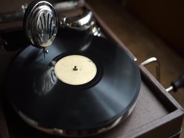 An old gramophone with a handle, twirling a black vinyl record. Retro vinyl record player. - Video