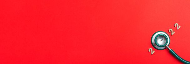 Estetoscopio número 2022 sobre fondo rojo idea creativa nueva tendencia banner médico cubierta del calendario de cerca con espacio de copia. Banner - Foto, Imagen
