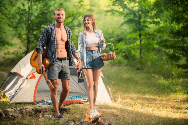 Romantic couple walking on camping, man with guitar. Outdoor adventure with friends on nature. - 写真・画像