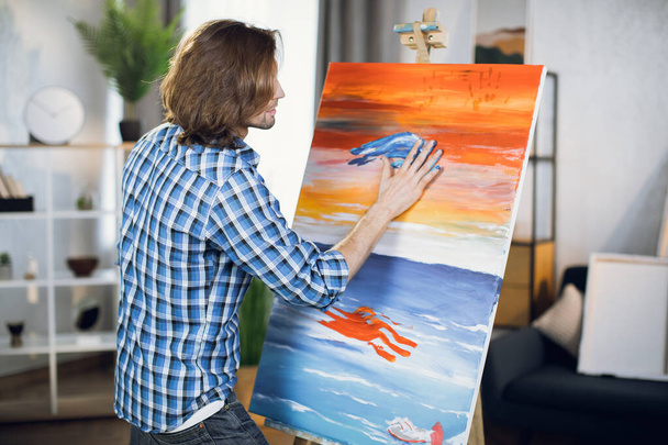 Creative man painting on canvas with hands - 写真・画像
