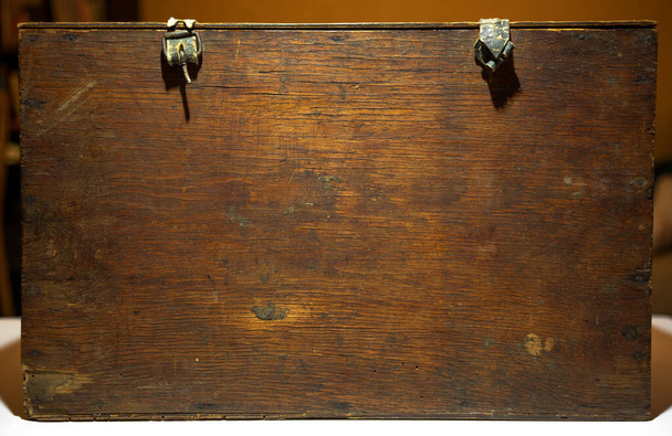 An old wooden box with clasps stands on a table in the house. - Fotó, kép