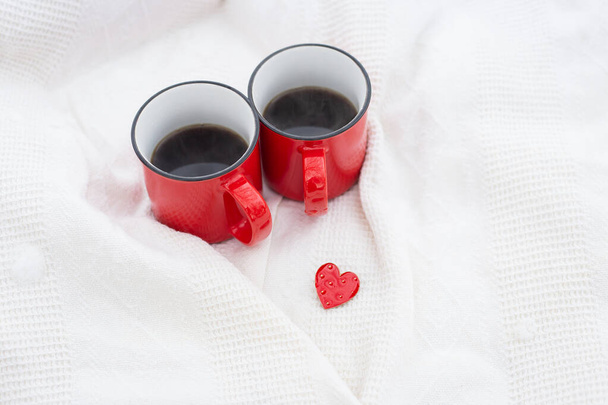 Two red cups of coffee together with a small red heart, coffee in bed. Surprise, valentine's day celebration concept - Fotoğraf, Görsel