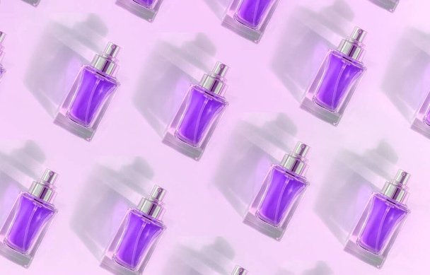Pattern of Transparent perfume bottle lying on pink violet background - Valokuva, kuva