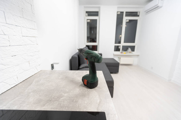 the screwdriver stands next to the new furniture and sofa at home. - Valokuva, kuva