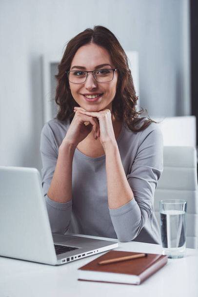 Young attractive businesswoman in casual clothes smiling and looking in camera while working in office - Foto, Bild