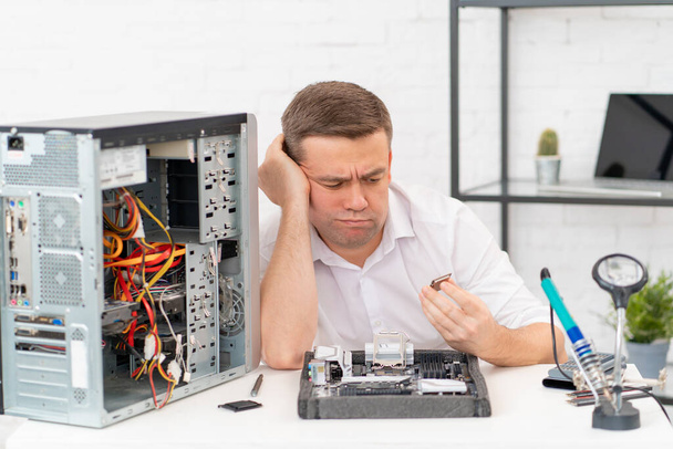 computer workshop. professional services. sad repairman with a processor in hand - 写真・画像