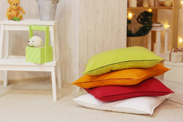παιδικό playroom με χρωματιστά μαξιλάρια, αρκουδάκι, παιχνίδια χαλί, βιβλίο και λευκά έπιπλα close up φωτογραφία - Φωτογραφία, εικόνα