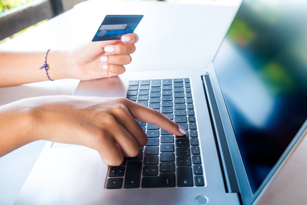キーボードの女性の手と電子商取引のウェブサイトで買い物のためのクレジットカードを保持します。広告、販売、プロモーションに役立ちます。ウェブサイトのスクリーンショットでカスタマイズ可能な画面. - 写真・画像