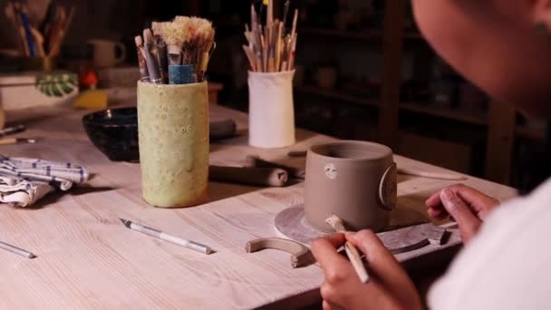 スタジオの陶器-女性の陶芸家はカップにハンドルを試してみて、それを見て - 映像、動画