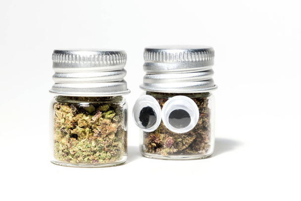 closeup of marijuana in jars and cannabis character with eyes on white background  - Foto, immagini