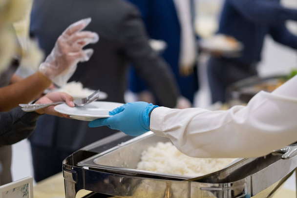 closeup hand wearing gloves scooping food, catering, dinner time, prevent Coronavirus disease (covid 19 - Photo, Image