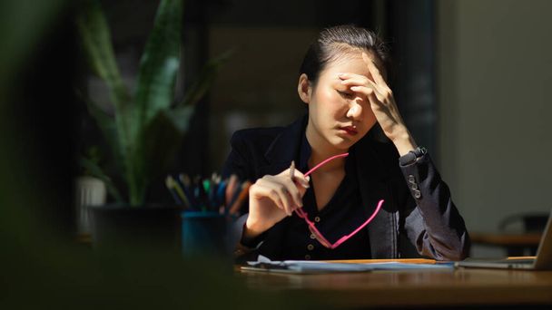 A businesswoman has a headache or eye-strain after having overworked. stressed, eye fatigue, exhausted. - Zdjęcie, obraz