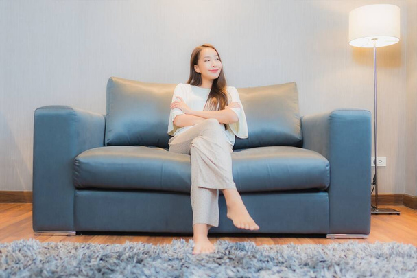 Портрет красива молода азіатка розслабляється на дивані в інтер'єрі вітальні
 - Фото, зображення