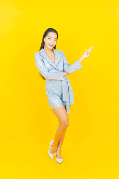 Portrait beautiful young asian woman smile with action on yellow color background - 写真・画像