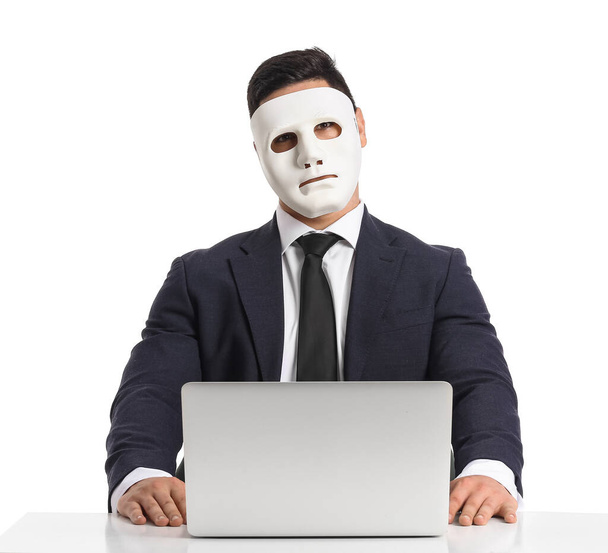 Hacker with laptop and mask at table on white background - Zdjęcie, obraz