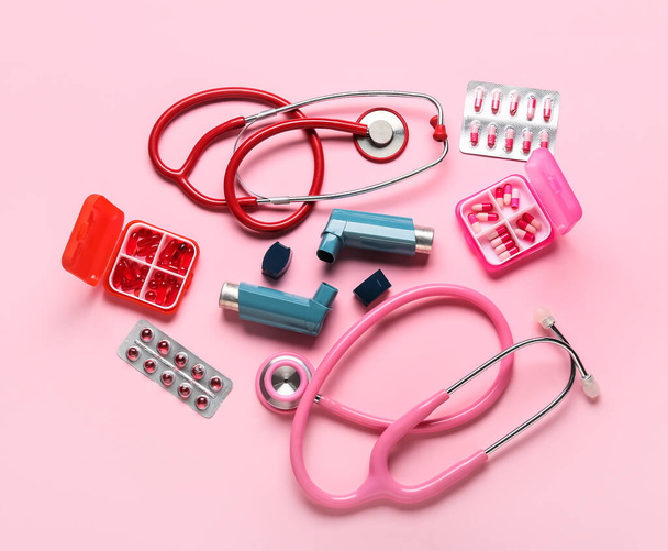 Asthma inhalers, stethoscopes and pills on pink background - Photo, Image