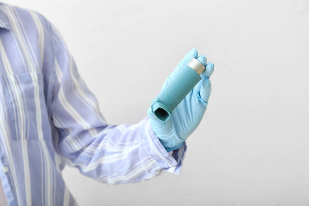 Woman holding asthma inhaler on light background - Foto, immagini