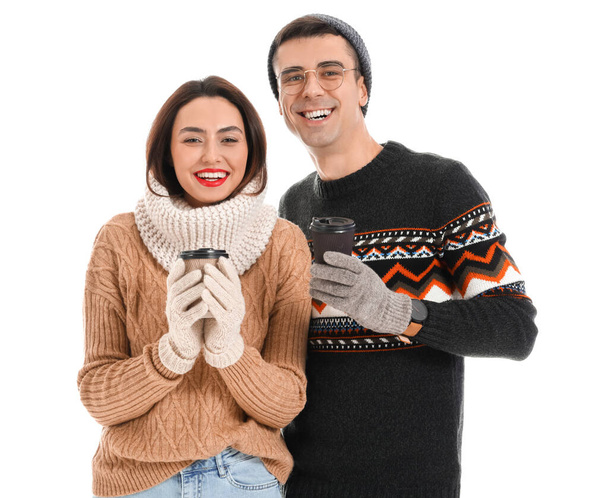 Glückliches junges Paar in warmen Pullovern und mit Kaffee auf weißem Hintergrund - Foto, Bild