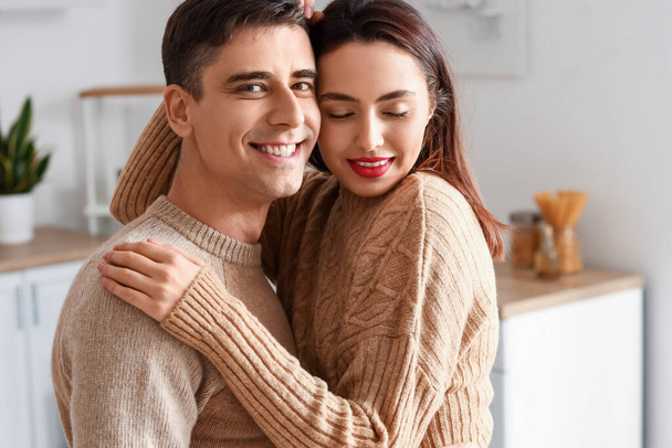 Feliz joven pareja usando suéteres calientes en casa - Foto, imagen