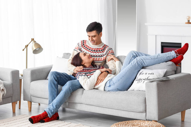 Ευτυχισμένο νεαρό ζευγάρι που φοράει ζεστά πουλόβερ στο σπίτι - Φωτογραφία, εικόνα