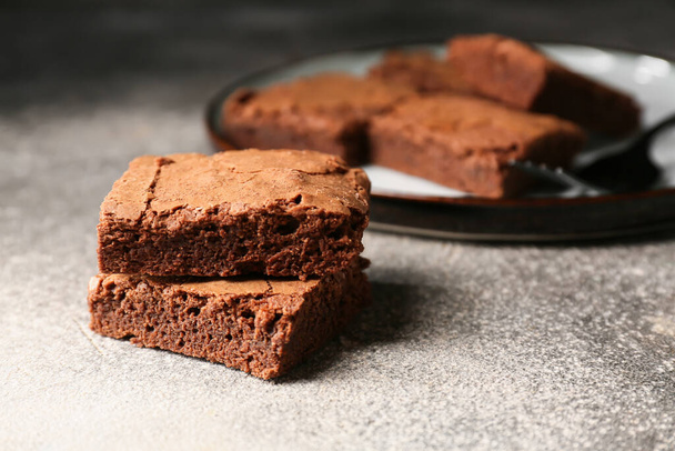 Pieces of tasty chocolate brownie on grey background - Photo, Image