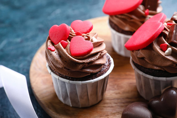 Wooden board with tasty chocolate cupcakes for Valentine's Day on black background, closeup - Фото, зображення