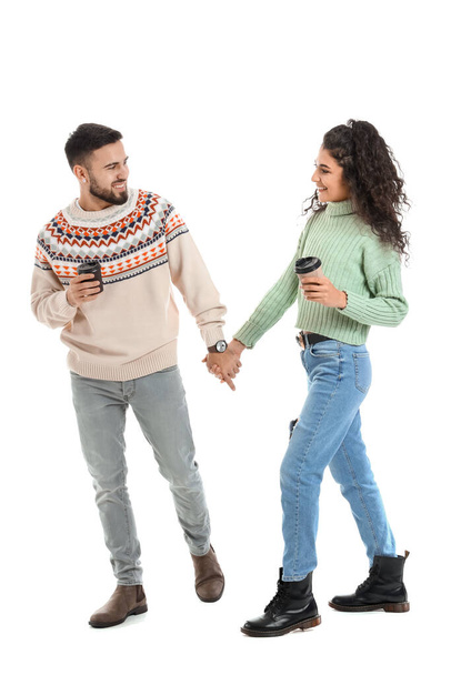 Happy young couple in warm sweaters and with coffee on white background - Zdjęcie, obraz