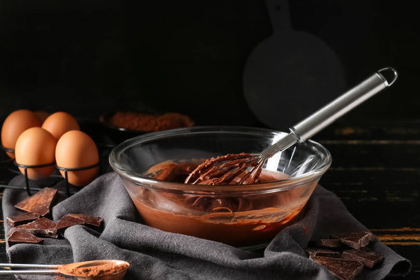 Bowl with fresh dough for preparing chocolate brownie on black background - 写真・画像