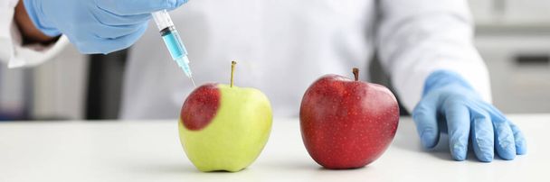 Scientist in laboratory makes injection into apple closeup - Photo, Image