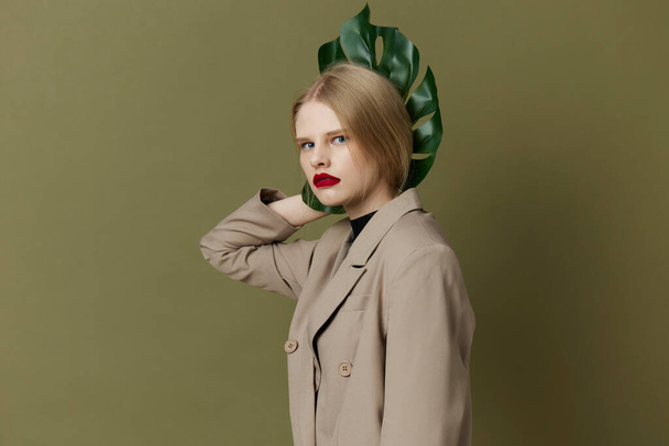 ブロンド女性緑のヤシの葉コート明るいメイクライフスタイルポージング - 写真・画像