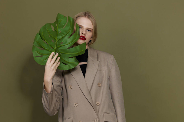 гламурная женщина в пальто красные губы модные пальмовые листья студия модель без изменений - Фото, изображение