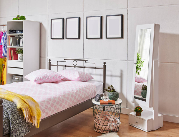 Cama de metal en el dormitorio, fondo de pared blanco, marco, armario, ropa y estilo manta. - Foto, imagen