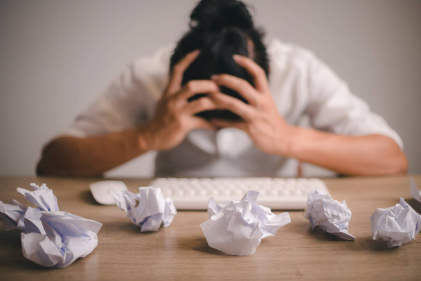 Businessman sitting with head in hands at desk covered crumpled papers. Office worker tired of too much difficult unproductive work. Stressed male entrepreneur has no idea what to do with problem - Fotó, kép