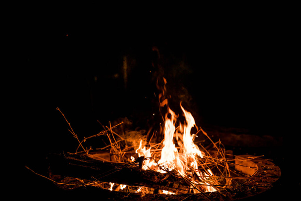 火と炎だ。炎と燃える火花が閉じ、火のパターン。火からの炎だ。夜のたき火、ログを火災にされ、火花飛ぶ。柔らかい焦点。浅い焦点効果. - 写真・画像