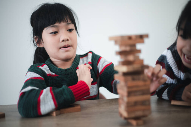 Cheerful Asian girl playing with wooden building blocks. Having fun and learning creativity. smart kid concept. - Photo, image